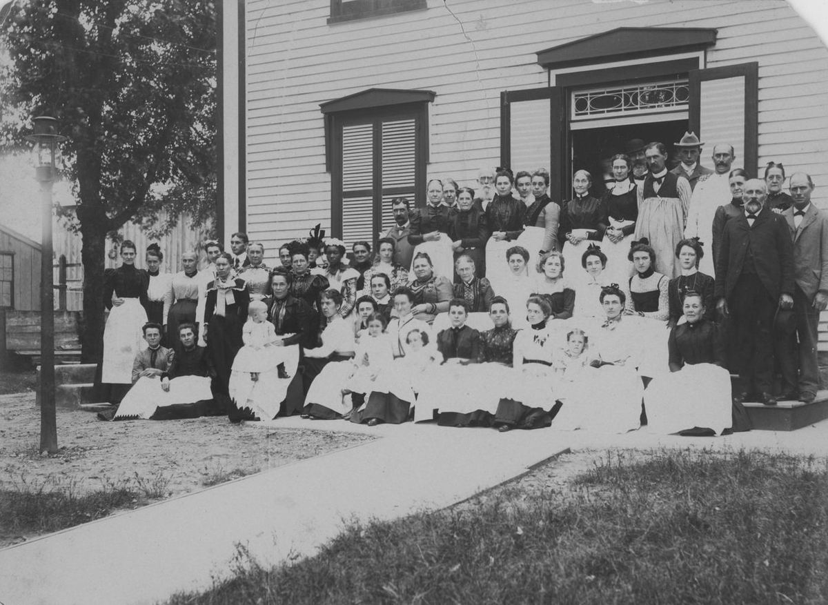 The congregation crowded before the church door, women in white seated in the front rows.
