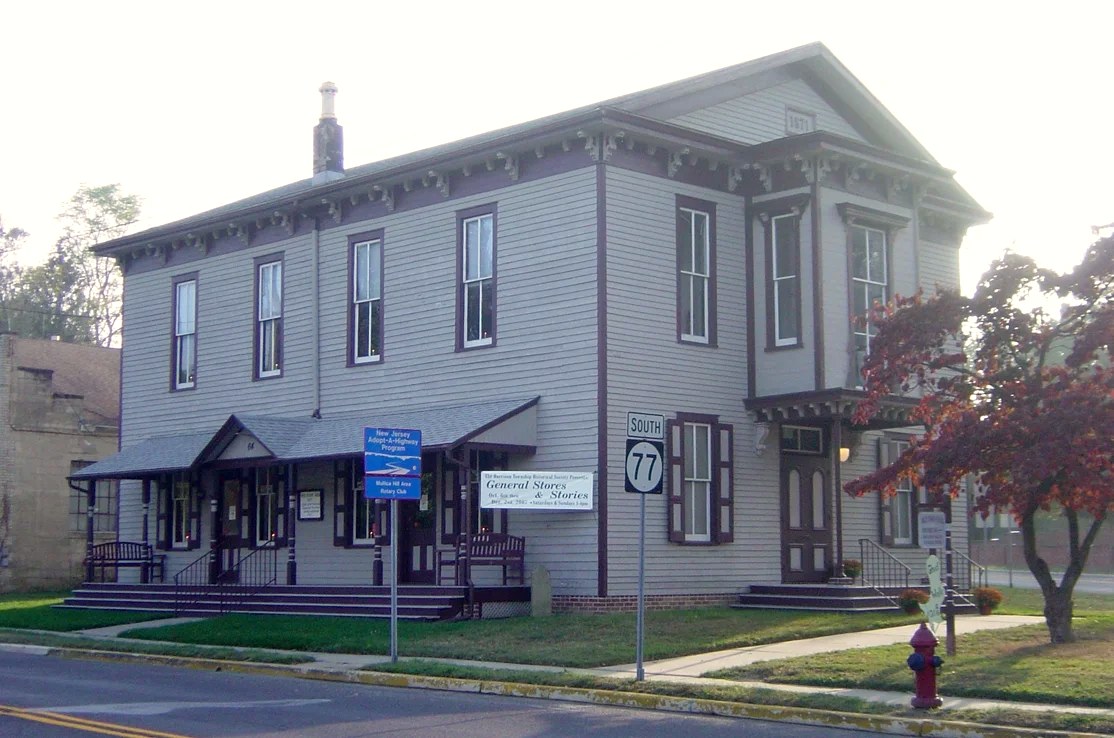 The hall today with twin porches over the sidewalk, marker signs out front, an autumn tree at the corner.