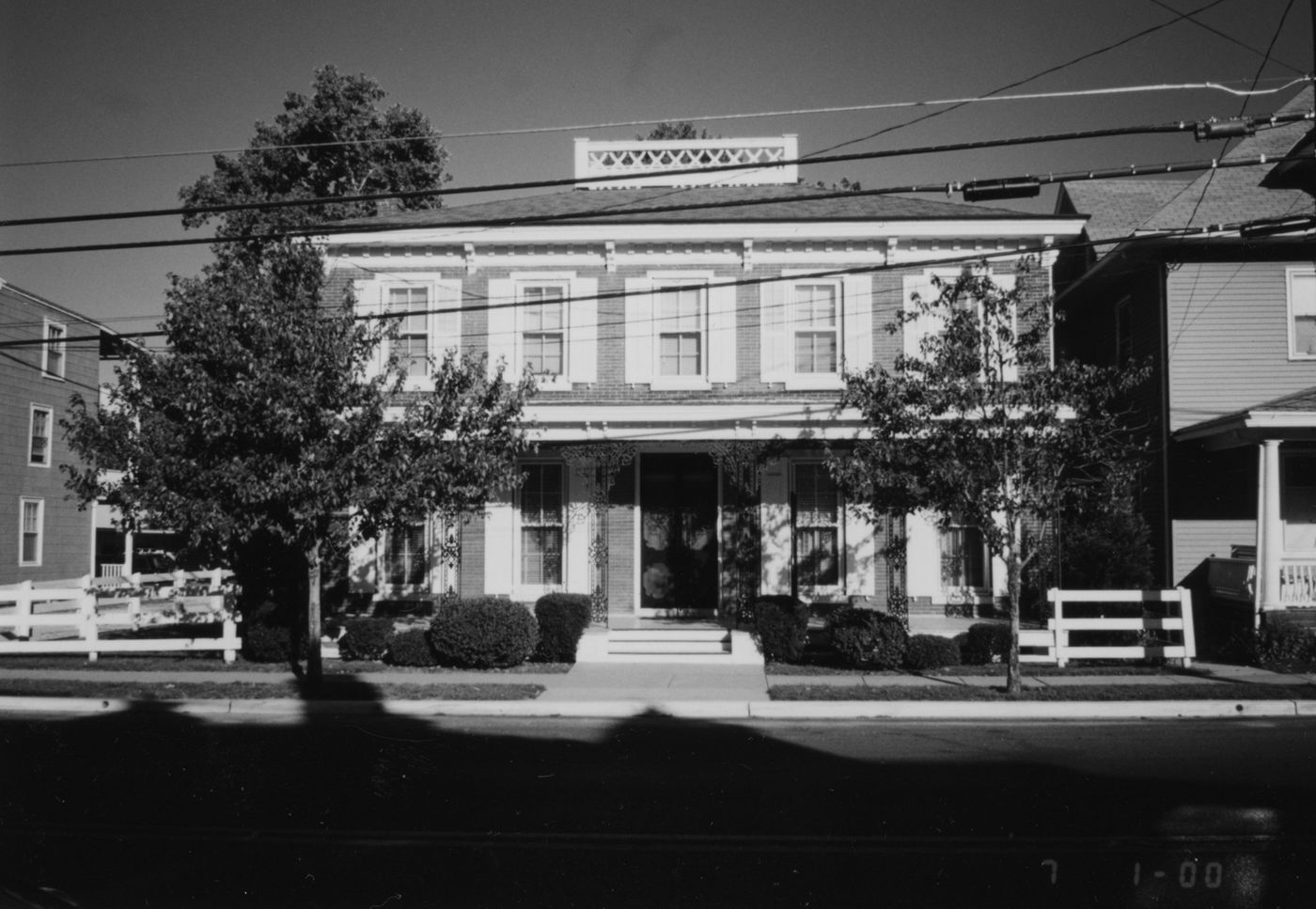 The square house with a bracketed cornice at its flat roofline and a centered entrance.