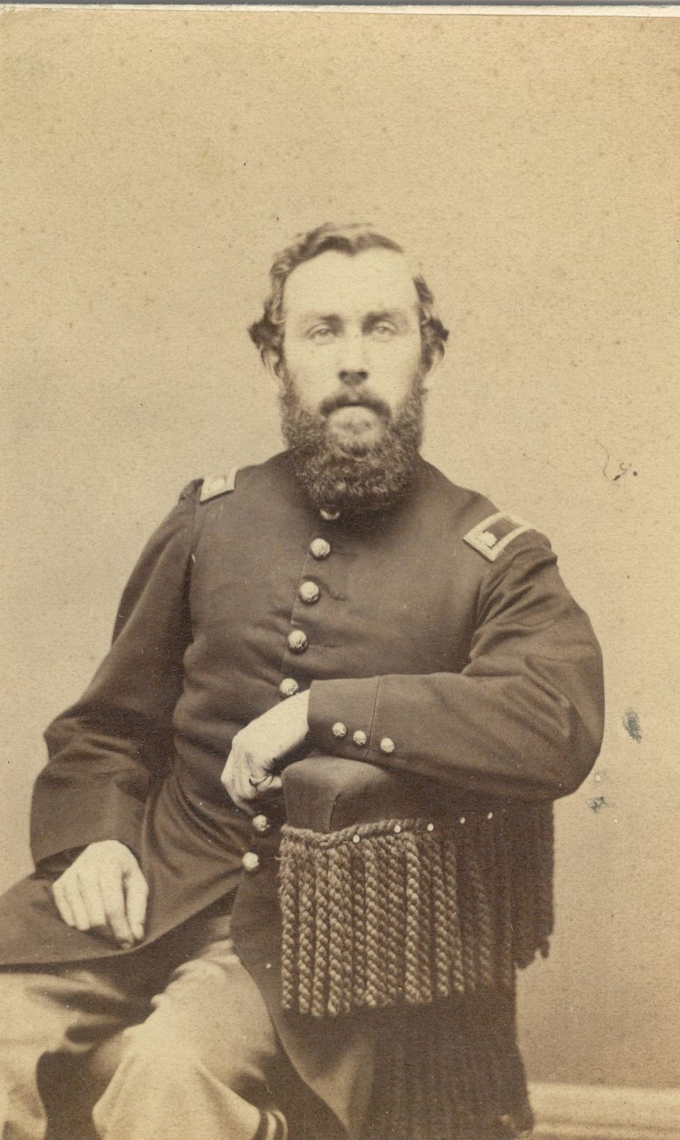 Studio portrait of a bearded officer seated in uniform.