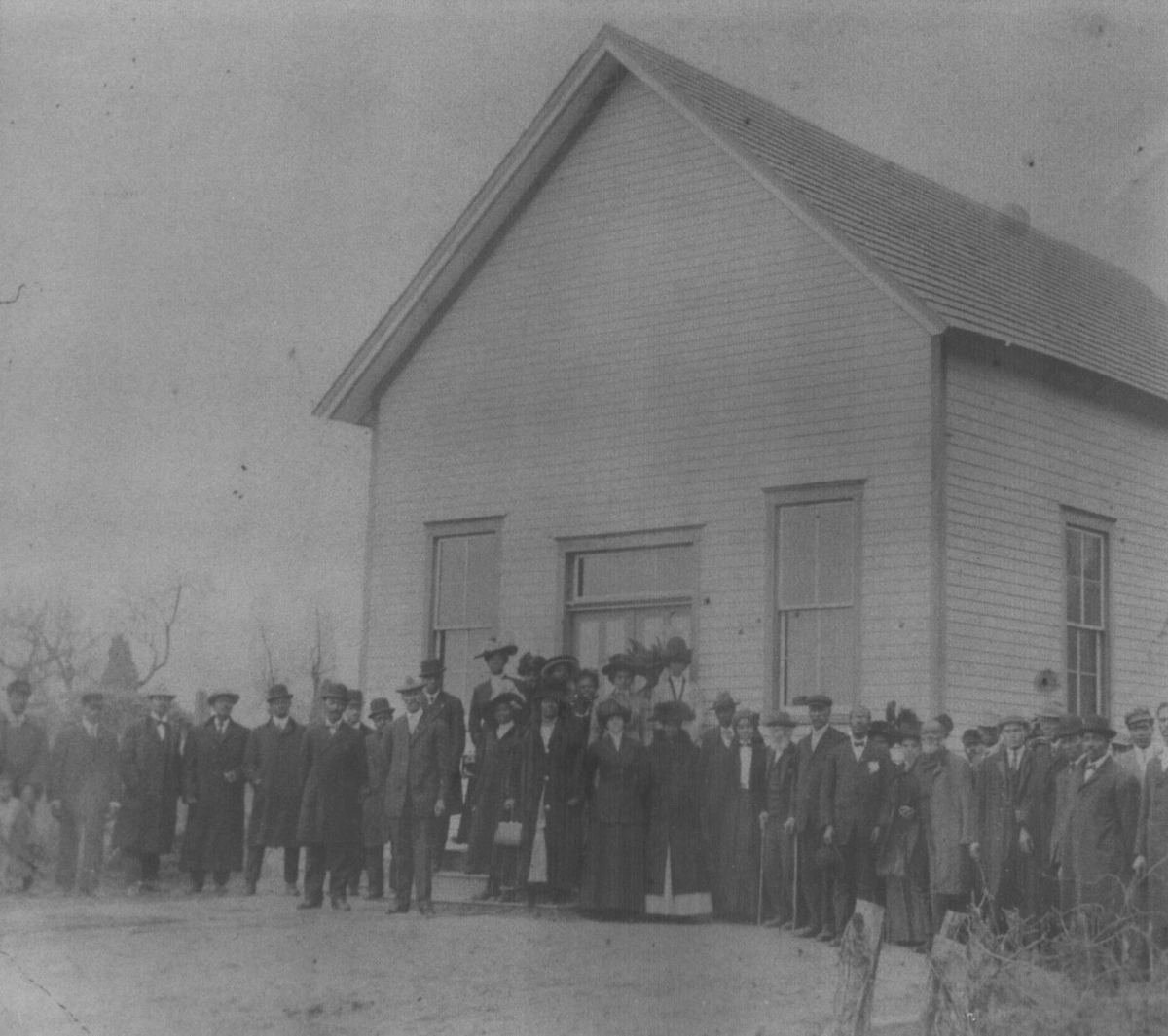 The congregation lined up in winter coats before the small white church.