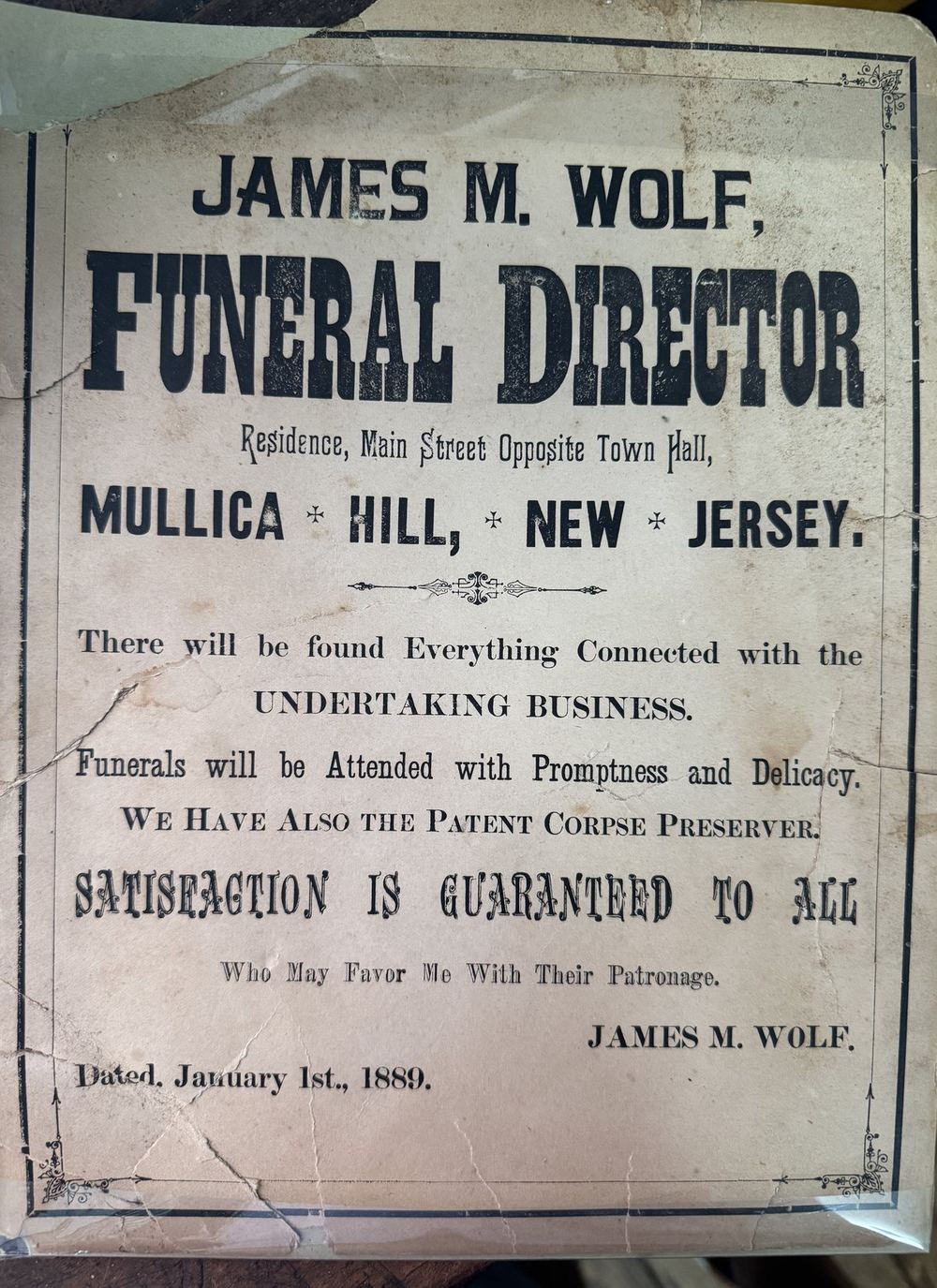 The printed handbill, James M. Wolf Funeral Director in heavy type, its promises in smaller lines below.